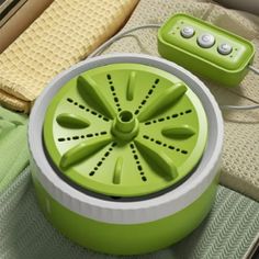 a green portable speaker sitting on top of a bed next to a pillow and remote control