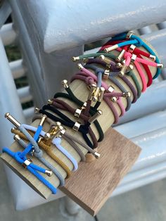 a bunch of different colored cords on top of a wooden board with gold hardwares