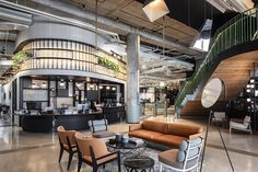 an office lobby with couches, chairs and tables in front of a spiral staircase