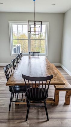 a dining room table with six chairs and a bench in front of a large window