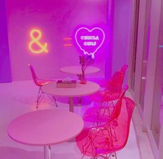 pink chairs and tables in a room with neon lights