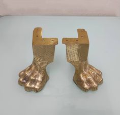 pair of gold colored metal feet on white surface with light blue back ground and wall in background