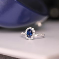 a blue and white diamond ring sitting on top of a table next to a bowl