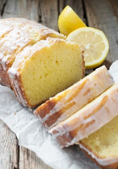 a loaf of lemon pound cake sitting on top of a piece of wax paper next to sliced lemons