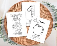 three baby's first book coloring pages sitting on top of a wicker basket