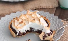 a chocolate cream pie on a silver plate with a fork and glass of milk in the background