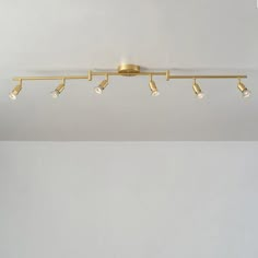 a ceiling light with five lights on each side and four bulbs in the middle, against a white wall