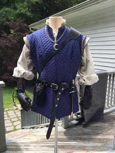 a mannequin wearing a blue quilted vest and black gloves on a porch