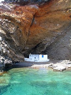 a small white house sitting on top of a cliff next to the ocean