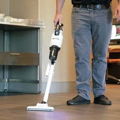 a man standing on the floor with a vacuum in his hand