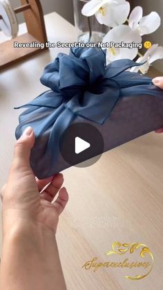 a person holding a blue gift box with a bow on it