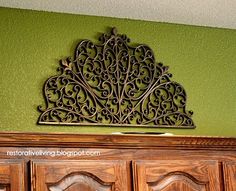 an ornate metal piece on the wall above a wooden door in a green walled room