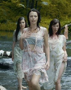 three women are walking in the water with one woman holding her hand up to her chest