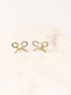 Bows and pearls? The perfect pair is all-in-one. The Pearl Bow earrings feature a delicate and minimalistic gold bow with a small cultured pearl at the center of the bow. Size: 1/4" x 1/2". Materials: 14k plated gold brass with cultured pearl. Nickel-free, hypoallergenic. Founded by Kilee Nickels and designed to inspire confidence, Nickel & Suede is a Woman Owned Business that empowers women to be their most authentic selves and make every day brave. Made and based in Kansas City, Missouri. Tiny Elegant Pearl Earrings For Gifts, Feminine Gold Pearl Earrings For Gift, Elegant 14k Gold Jewelry With Bow, Elegant 14k Gold Jewelry With Bow Detail, Minimalist Gold Jewelry With Bow, Gold Pearl Earrings With Bow As Gift, Gold Pearl Earrings With Bow For Gift, Gold Dainty Earrings With Bow, Dainty Gold Earrings With Bow