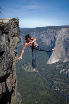 a man on a rope high up in the air with his hands and legs stretched out