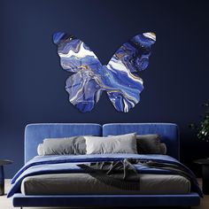 a bed with blue sheets and pillows in front of a painting on the wall above it