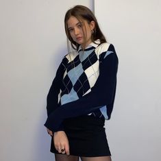 a young woman is posing in front of a white wall with her hands on her hips