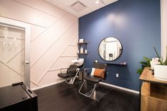 a hair salon with blue walls and black chairs in front of a mirror on the wall