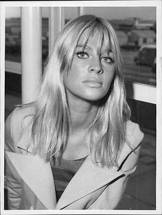 a black and white photo of a woman with long hair sitting in front of a window