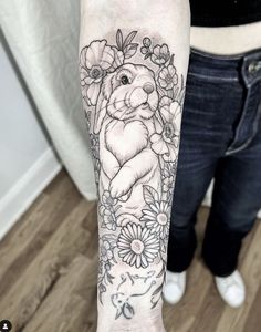 a woman's arm with flowers and a bunny tattoo on the left side of her arm