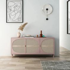 a pink cabinet in the corner of a room with two pictures on the wall and a clock above it