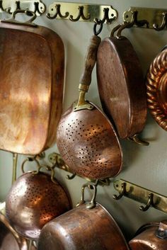 copper pots and pans hanging from hooks on a wall in an antique shop or restaurant