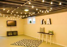 an empty room with lights strung from the ceiling and rug on the floor in front of it