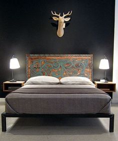 a bed with a deer head mounted on the wall above it and two lamps next to it