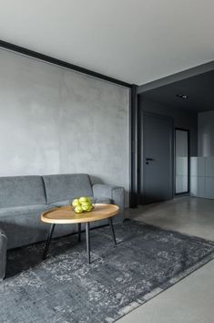 a grey couch sitting next to a wooden table on top of a gray carpeted floor