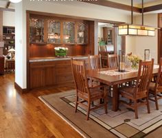 a dining room table and chairs in front of an open kitchen area with wooden flooring