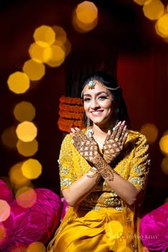 a woman with her hands on her chest posing for a photo in front of some lights