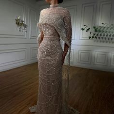 Made to order dresses will ship in 2-3 weeks as they are custom created. Unleash your inner goddess in our Luxurious Beaded Cape Dress! Featuring a champagne beaded bodice and a removable cape, this dress exudes opulence and elegance. Cinch your waist with the included satin lined belt for a flattering silhouette. Perfect for any special occasion, this dress drips with luxury. SIZE & FIT Model wears: UK 8/ EU 36/ US 4 Model's height: 171cm/5'7.5” LOOK AFTER ME Dry clean only Made to order dresse Long Cape, Pearl Beading, Embellished Gown, Engagement Dresses, فستان سهرة, Dress Dusty, Cape Dress, Gowns With Sleeves, Glam Dresses