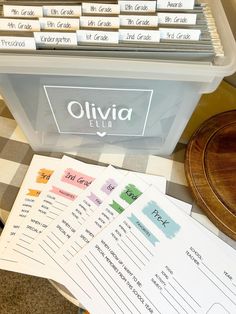 a table topped with lots of papers next to a plastic container filled with writing paper