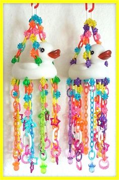 two colorful wind chimes hanging from the side of a white wall next to each other