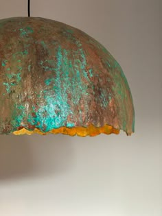 a green and brown lamp hanging from a ceiling