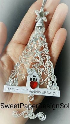 a hand holding a silver christmas tree ornament with a red heart on it