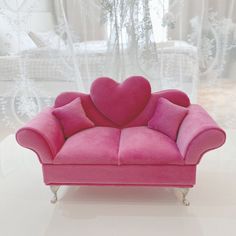 a pink couch with a heart shaped pillow on it