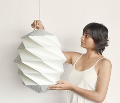 a woman is holding a paper sculpture in front of her face