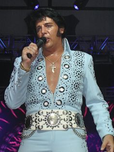 the man is dressed in elvis clothing and holding a microphone