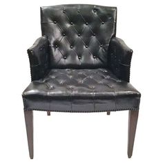 a black leather chair with wooden legs and studding on the armrests against a white background