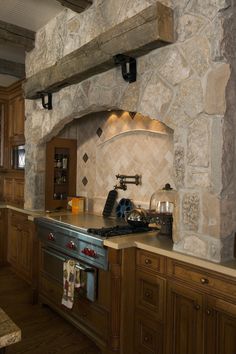 a kitchen with an oven, stove and counter tops in stone walling that matches the wood cabinetry