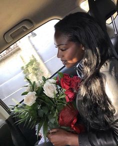 a woman sitting in the back seat of a car holding flowers