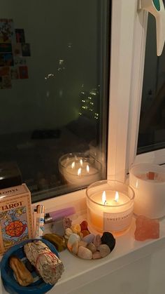 candles and other items are sitting on a window sill in front of a book