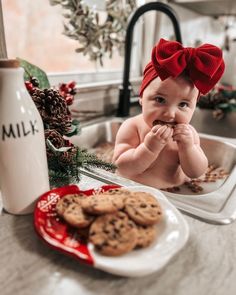 a baby sitting in a sink with cookies and milk