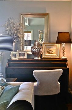 a living room filled with furniture and a mirror on top of a dresser next to a lamp