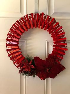 a wreath made out of red sticks and poinsettis hangs on the front door