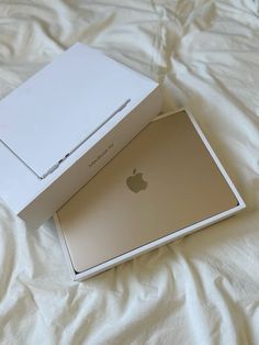 an apple box sitting on top of a bed next to a white box with the lid open