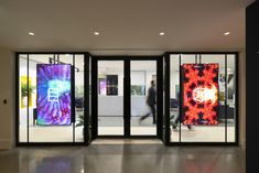 an entrance to a building with glass doors and artwork on the walls in front of it