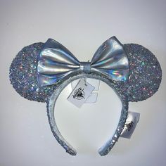 there is a silver minnie mouse ears headband with a bow at the top and sequins on it