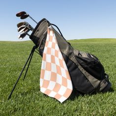 an orange and white checkered tie laying on top of a golf bag